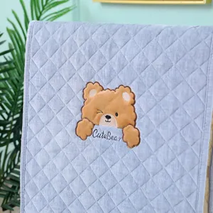 Close-up of cute bear embroidery on grey quilted velvet chair cover protector