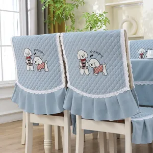 Détail d'une housse de chaise matelassée bleu clair avec broderie chiot et volants en dentelle