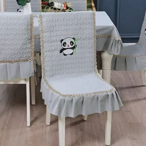 Close-up view of a grey quilted chair cover featuring cute panda embroidery and lace trim