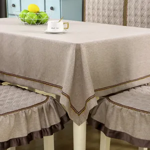 Close-up detail of tan linen-style tablecloth and chair cover with embroidery trim