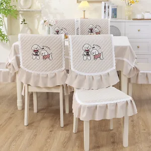 Vue détaillée des housses de chaise matelassées beiges avec broderies de chiots