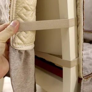 Detailed view of the elastic fastening strap on a quilted beige dining chair cover