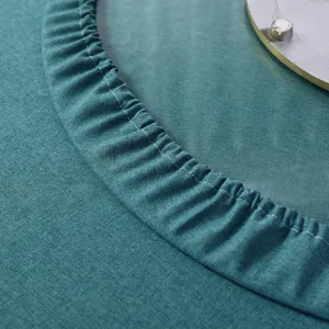 Primo piano del bordo elasticizzato di una tovaglia rotonda verde acqua con trama del tessuto