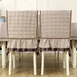 Back view of quilted khaki chair covers with ruffled skirts and matching tablecloth.