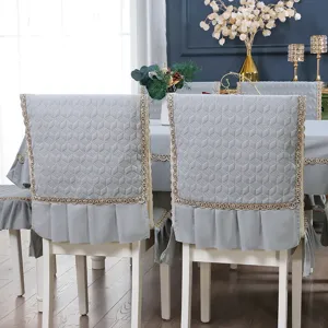 Close-up of gray quilted chair cover with elegant golden lace trim and pleated hem.