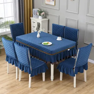 Set di tovaglia e coprisedie trapuntati blu con volant in una accogliente sala da pranzo.