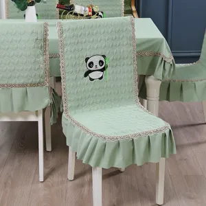 Close-up of quilted sage green chair cover with cute panda embroidery and lace trim