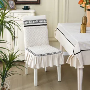 Vue détaillée d'une housse de chaise matelassée crème avec dentelle et volants décoratifs.