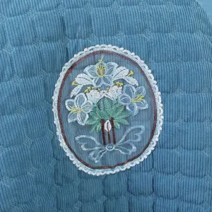 Detail of blue corduroy chair cover featuring a delicate white lace floral embroidery