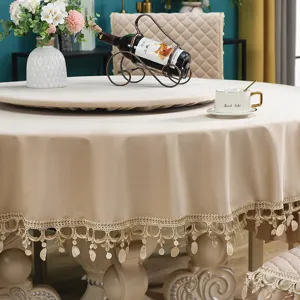 Elegante tovaglia rotonda beige con frange in pizzo decorativo e copri piatto girevole