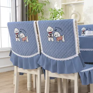 Détail de la housse de chaise matelassée bleue avec broderie chiot et bordure en dentelle.