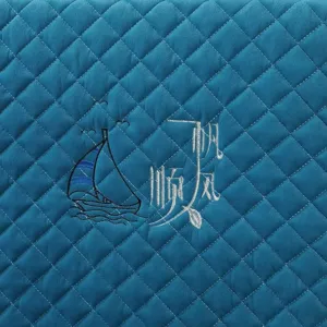 Detailed view of quilted chair cover fabric with embroidered sailboat and calligraphy