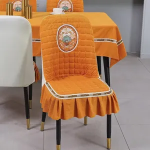 Detail view of orange quilted chair cover with elegant floral embroidery and ruffled skirt