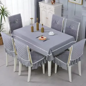 Gray quilted tablecloth and chair cover set with lace trim in a home dining setting