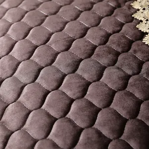Macro detail of a brown velvet quilted chair cover featuring elegant golden lace decorative trim.
