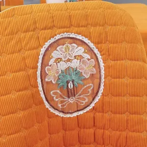 Close-up of floral embroidery detail on orange corduroy chair cover backrest.