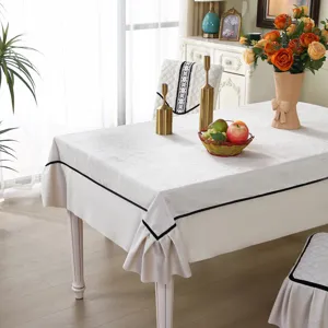 Elegant white tablecloth with black piping and ruffle details on a dining table