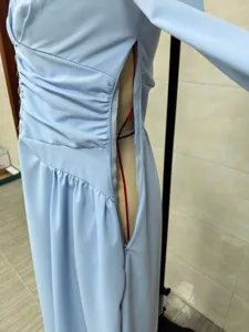 Close-up detail of side zipper and waist ruching on an elegant light blue maxi dress