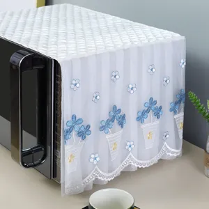Close-up of white lace microwave dust cover with blue floral embroidery