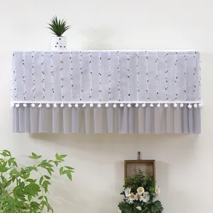 Dettaglio della copertura per condizionatore a muro con pompon e volant in tulle grigio