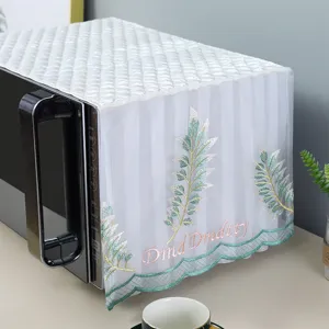 Detailed view of white lace microwave dust cover with green leaf embroidery and wavy edge