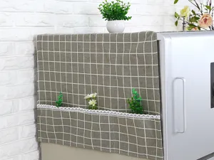 Detalle de funda para nevera a cuadros grises con bolsillos laterales y encaje