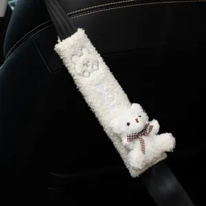 Close-up detail of white fluffy bear car seat belt shoulder pad featuring cute plush bear doll