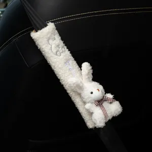 Close-up of white plush car seatbelt cover with cute rabbit doll and bow