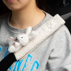 Close-up view of a cute plush rabbit car seat belt shoulder cover worn on a grey sweater