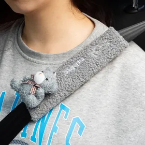 Detailed view of gray plush car seat belt cover featuring a cute teddy bear and embroidery
