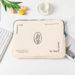 Κοντινό πλάνο κρεμ θήκης tablet με κομψό κέντημα και κεντρικό μονόγραμμα.