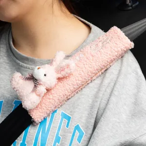Detalle de la funda protectora de cinturón de seguridad de conejo rosa en sudadera gris.