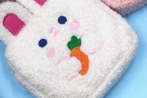 Close-up of cute rabbit embroidery on white plush fleece makeup pouch