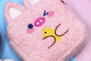 Close-up detail of cute pink plush pouch showing soft fuzzy texture and embroidery