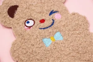 Detailopname van een schattige pluchen berenpasjeshouder met borduursel en strikje