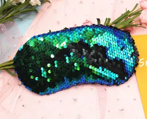 Close-up of reversible mermaid sequin eye mask with shimmering green and blue scales