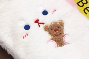 Close-up detail of soft white plush iPad sleeve featuring cute cartoon bear embroidery