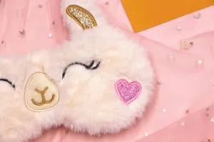 Close-up of soft plush alpaca sleep mask with pink glitter heart detail