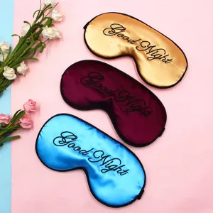 Detaillierte Nahaufnahme von drei farbenfrohen Satin-Schlafmasken mit Good Night Stickerei