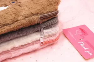 Close-up of zippers on stacked colorful plush tablet sleeves with a soft pink background