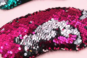 Dettaglio ravvicinato di una mascherina per occhi reversibile con paillettes a sirena rosa