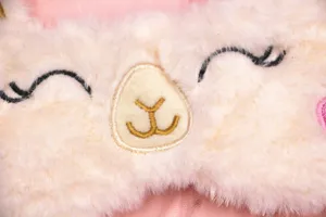 Macro view of soft plush alpaca sleep mask showing detailed embroidery and fluffy texture.