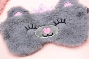 Macro detail view of a cute grey plush bear sleep mask with pink glitter crown
