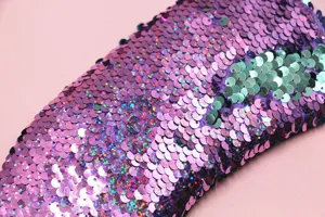 Close-up detail of reversible purple and teal mermaid sequins on a soft travel sleep mask