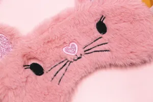 Macro view of pink plush sleep mask with cute embroidered cat face and heart nose