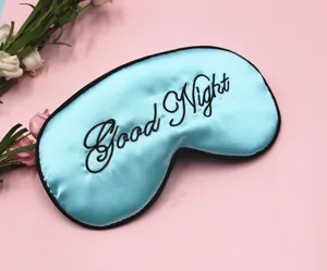 Detailansicht der schwarzen Good Night Bestickung auf einer hellblauen Schlafmaske