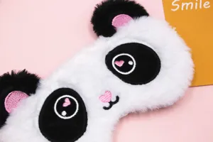Close-up detail of soft plush panda sleep mask featuring cute embroidered heart eyes