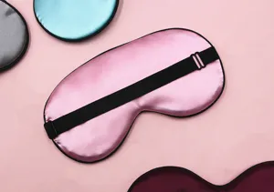 Detailed macro view of a pink satin sleep eye mask featuring an adjustable elastic strap