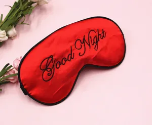 Detailaufnahme der roten Satin-Schlafmaske mit eleganter schwarzer Good Night-Stickerei