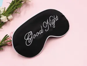 Detailaufnahme der schwarzen Schlafmaske mit weißem Good Night Stickerei und Blumen